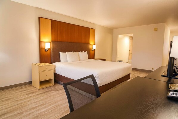Une chambre d’hôtel avec un grand lit, des tables de chevet, un bureau et une chaise.