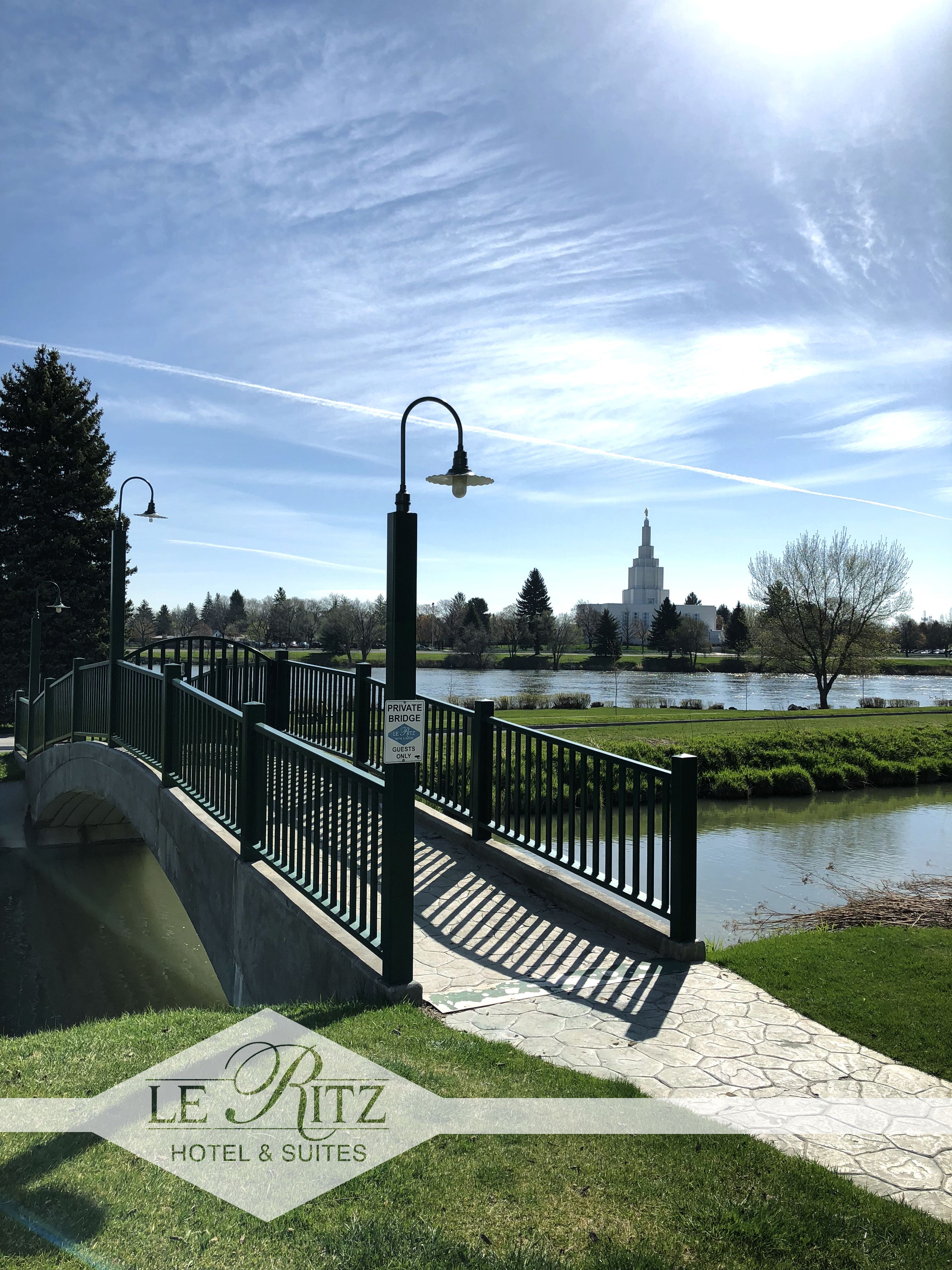 Un pont sur lequel est affiché un panneau indiquant qu’il est privé et réservé aux seuls invités, offrant une vue sur une étendue d’eau et un bâtiment situé au loin.