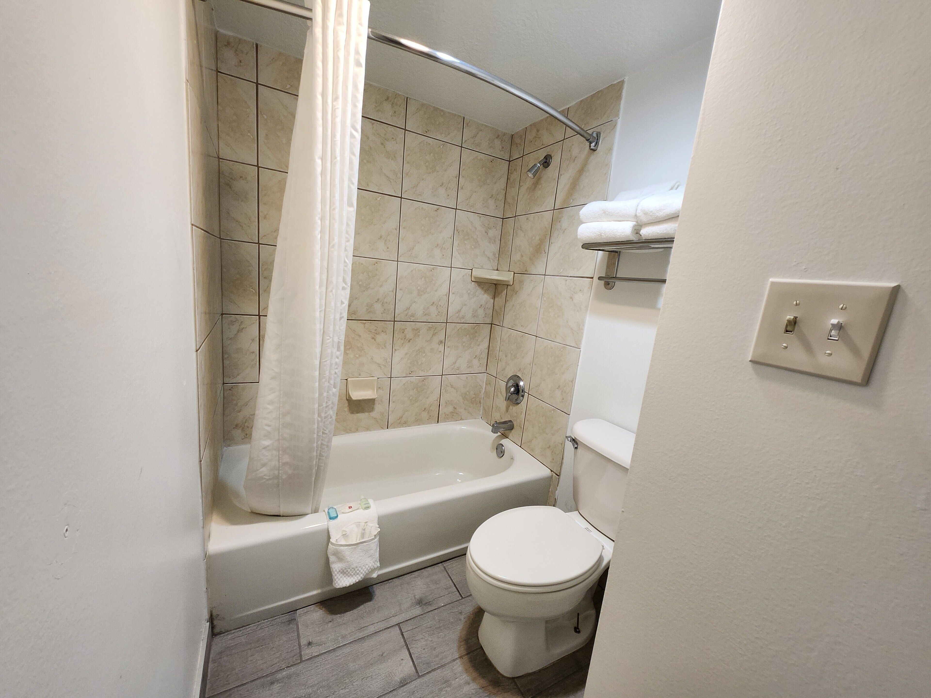 A bathroom with a bathtub, toilet, and a shower area.
