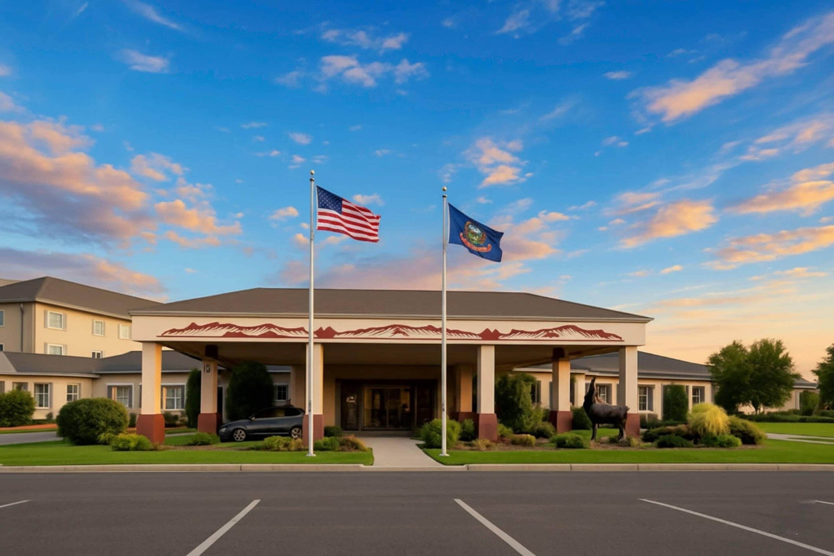 A hotel entrance with a covered area, two flags, and a parking lot.