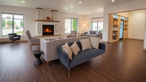 A spacious living room with a fireplace, modern furniture, and large windows.