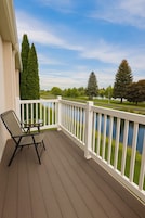 Una terraza de madera con barandilla blanca, una silla y una mesa.