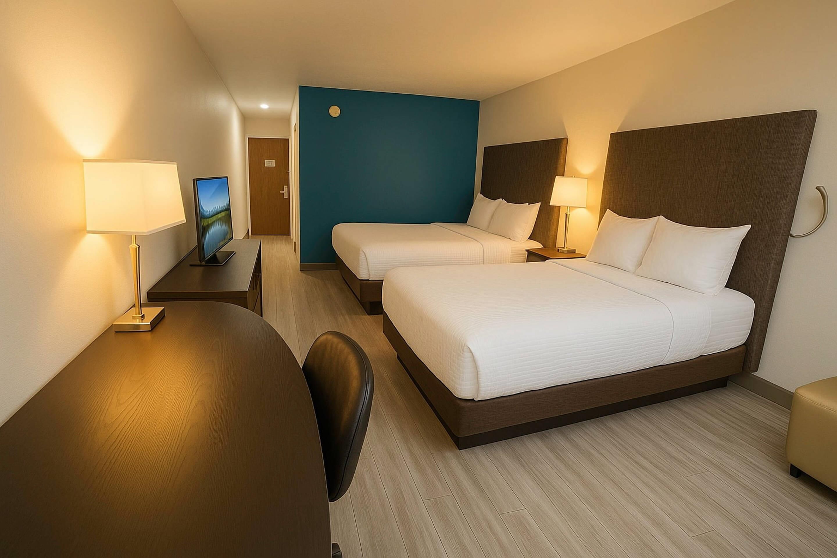A hotel room with two beds, a desk, and a chair.