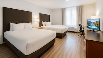 Habitación de hotel con dos camas, un escritorio con televisor y una ventana con cortinas.