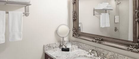 A bathroom with a marble sink, a large ornate mirror, and a towel rack with folded towels.