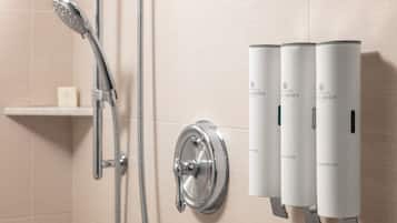 Ein Badezimmer mit Dusche, Toilette und drei Flaschen der Marke 'Brown' an der Wand.