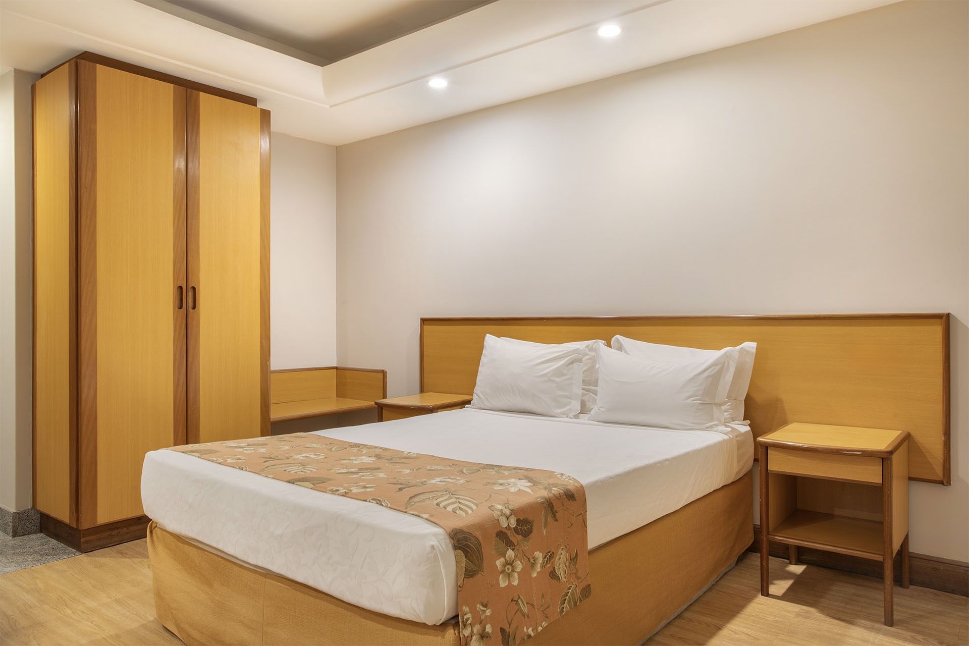 Ein Hotelzimmer mit einem großen Bett, einem Holzschrank, Nachttischen und einer Deckenleuchte.
