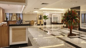 A hotel lobby with a reception desk, seating area, and a large potted plant. - Windsor Florida Hotel (Rio de Janeiro)
