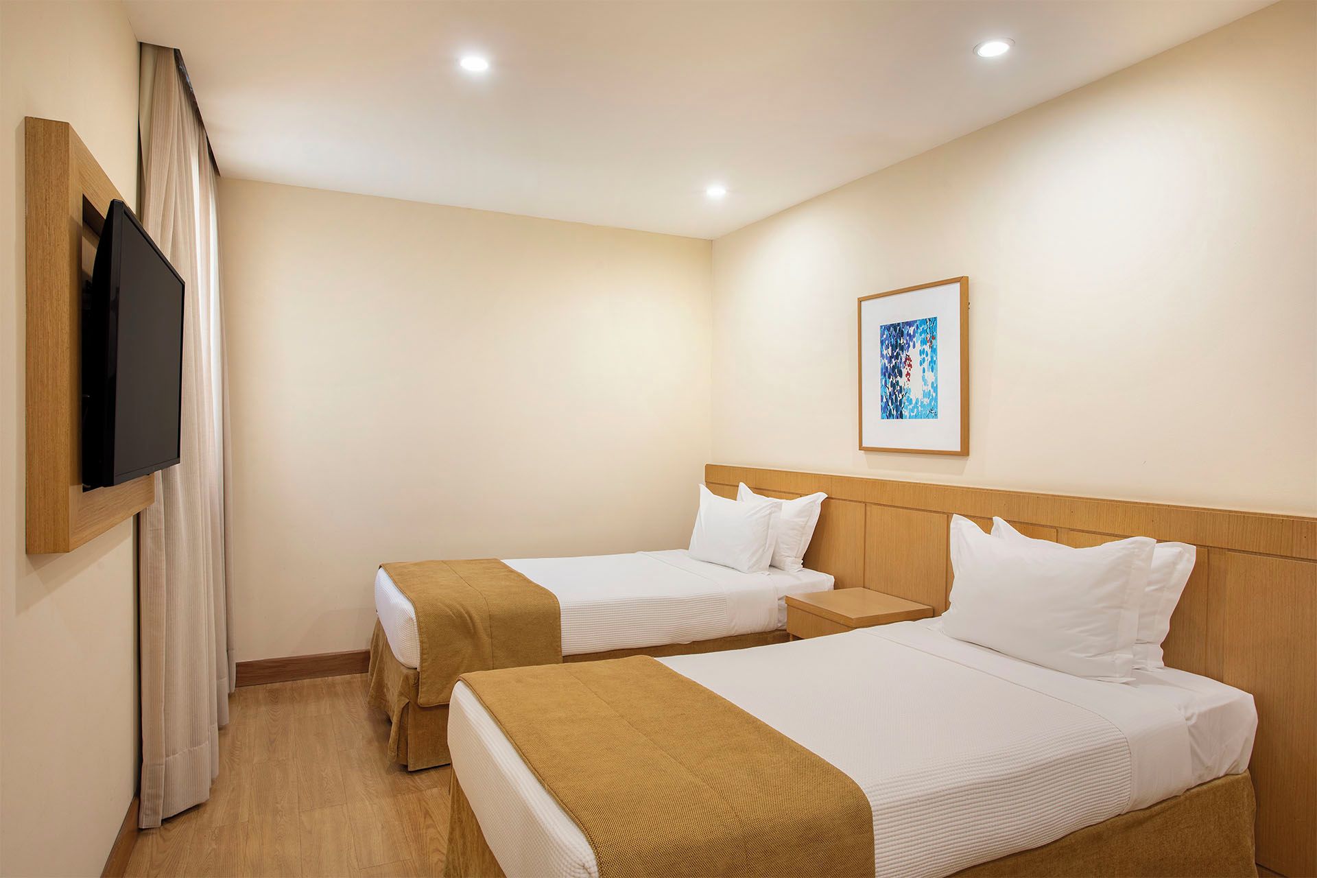 Habitación de hotel con dos camas, un televisor y un cuadro en la pared.