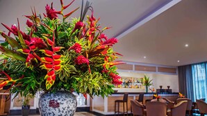 A hotel lobby with a large floral arrangement in a decorative vase, a bar area, and several seating arrangements. - Windsor Florida Hotel (Rio de Janeiro)