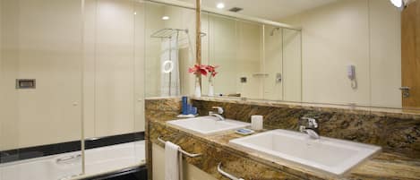 A modern bathroom with two sinks, a large mirror, and a glass shower enclosure.