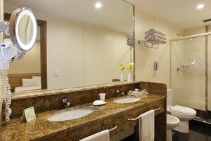 Un baño con dos lavamanos, un espejo grande, cabina de ducha de cristal y un inodoro.