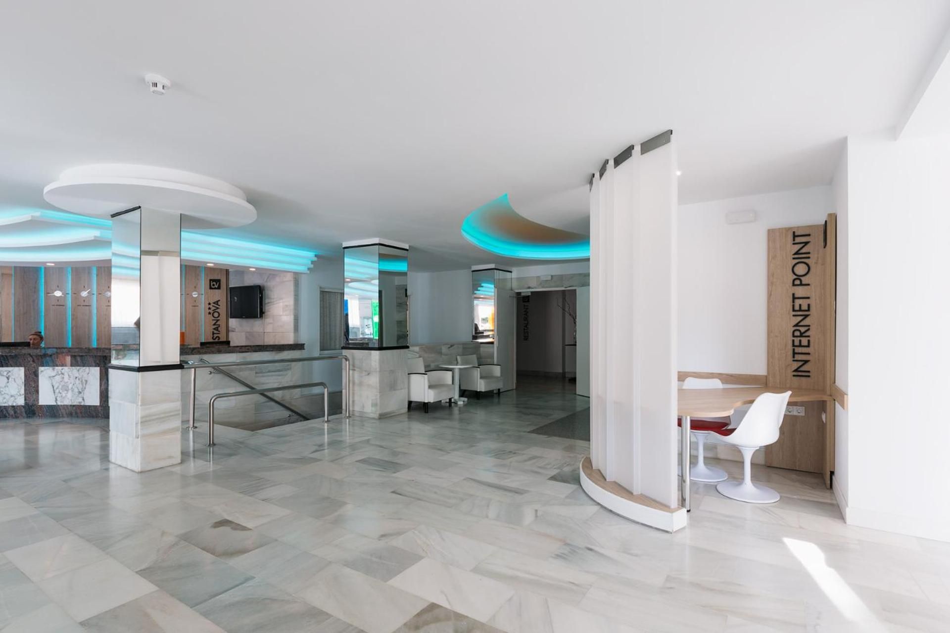 Een moderne hotel lobby met een receptiebalie, een zithoek en een internetpunt.