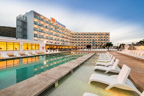 A hotel with a large pool, multiple balconies, and outdoor seating areas. - Hotel BelleVue Lagomonte (Alcúdia)