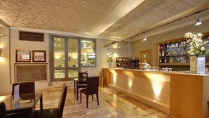 Una zona de bar con mostrador de madera, asientos y vistas a la sala contigua.
