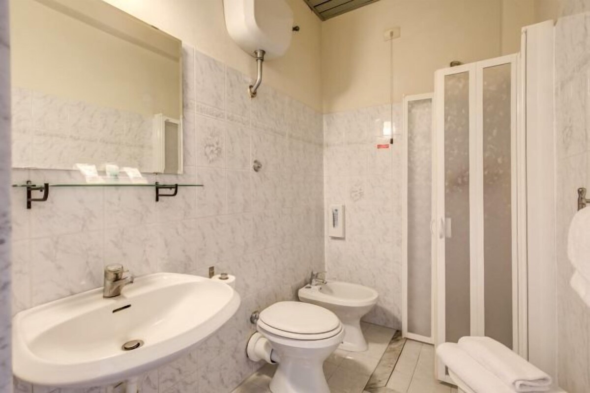 A bathroom with a sink, toilet, bidet, and a glass-enclosed shower area.