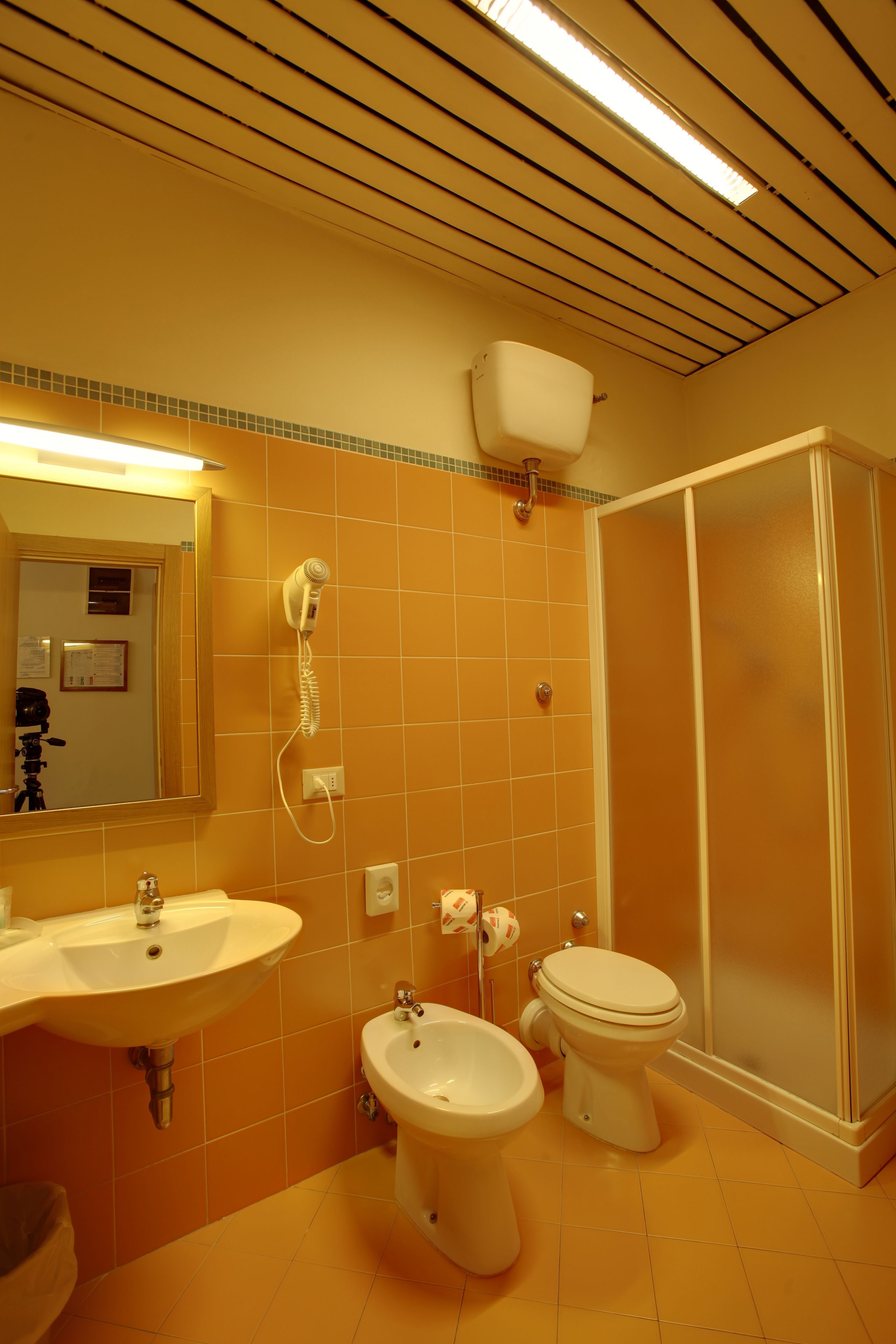 A bathroom with a sink, bidet, toilet, and a walk-in shower.