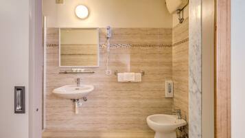 Un baño con lavamanos, espejo, toallero y bidé.