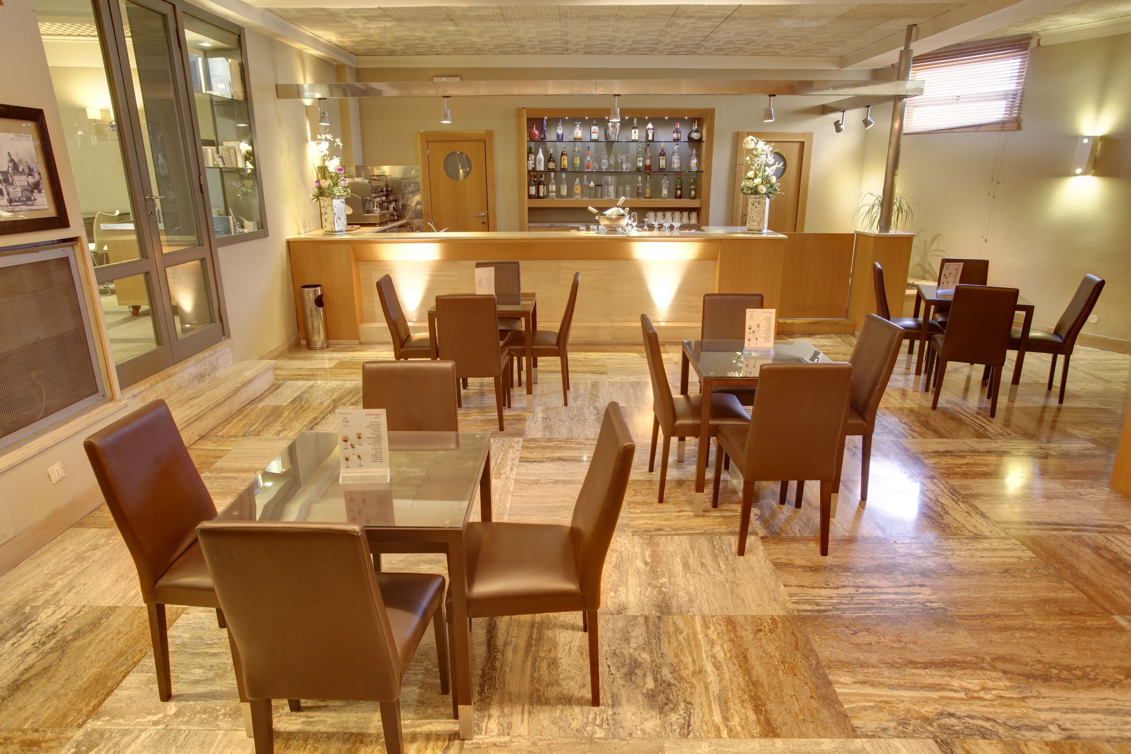 Un restaurant doté d’un bar, de chaises en bois et d’un sol en marbre.