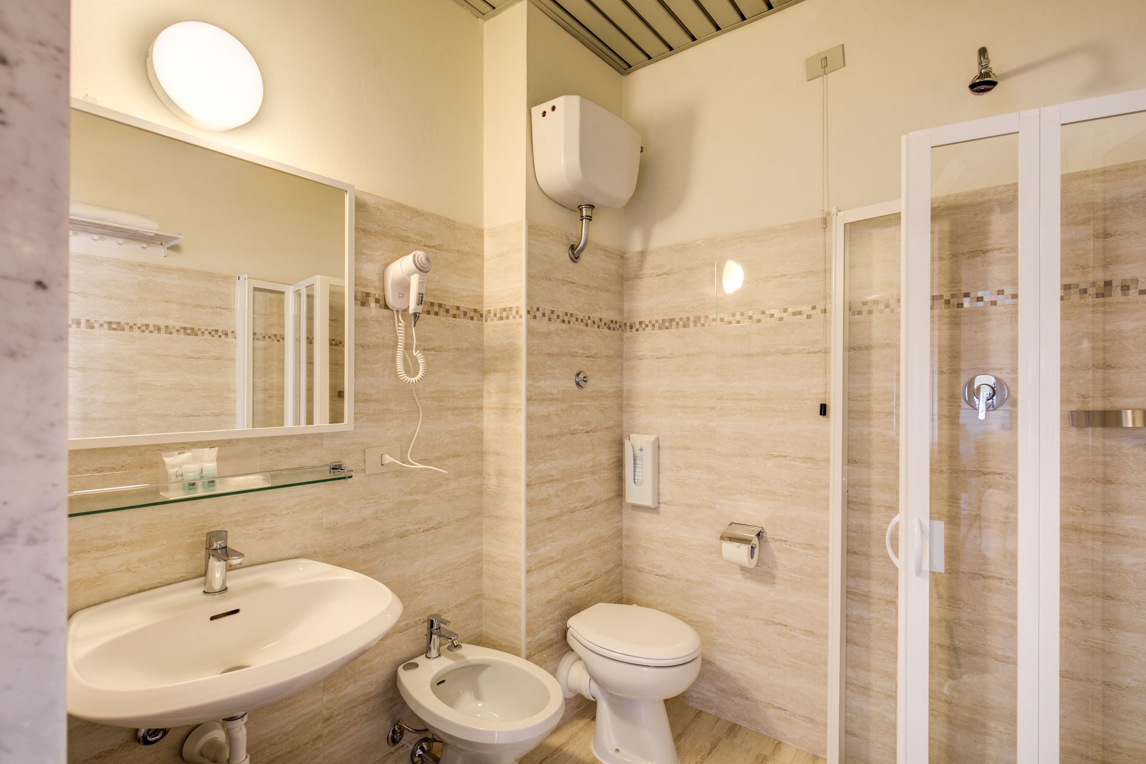 A bathroom with a sink, bidet, toilet, and glass-enclosed shower.