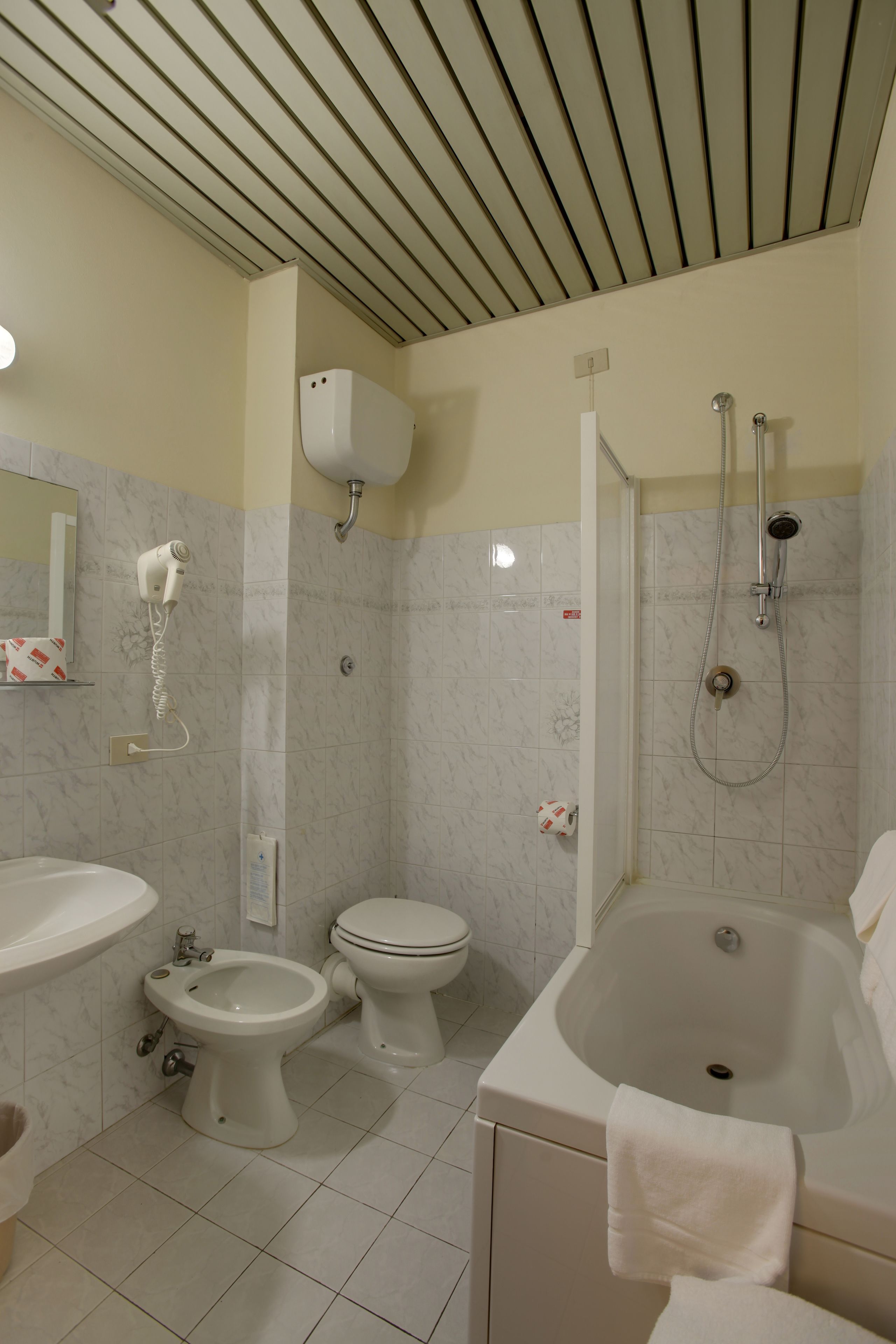 A bathroom with a toilet, bidet, sink, and bathtub.