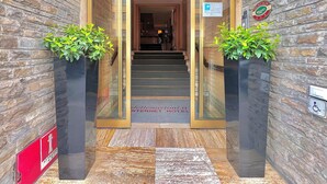 Fachada de hotel de piedra, puerta de cristal y escalera de acceso.