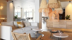 Una sala moderna con un sofá, dos mesas redondas y una silla de mimbre.