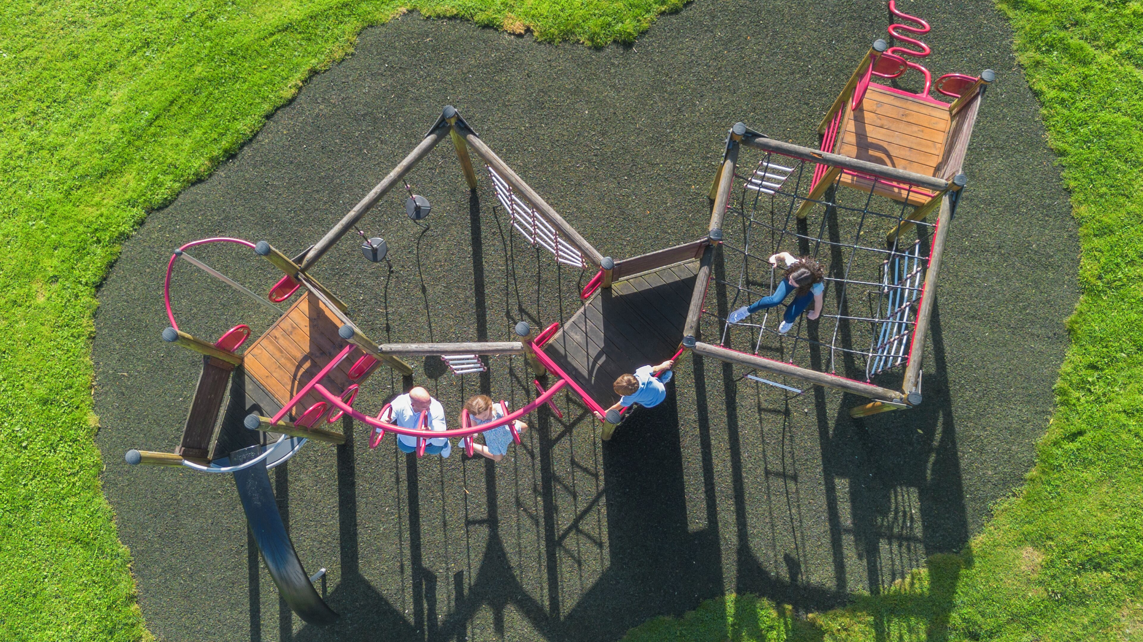 A playground with multiple play structures, including a swing set and a climbing frame.