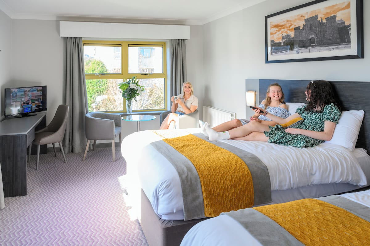 Ein Hotelzimmer mit einem Bett, einem Schreibtisch, einem Sessel, einem kleinen Tisch und einem Fenster mit Vorhängen.