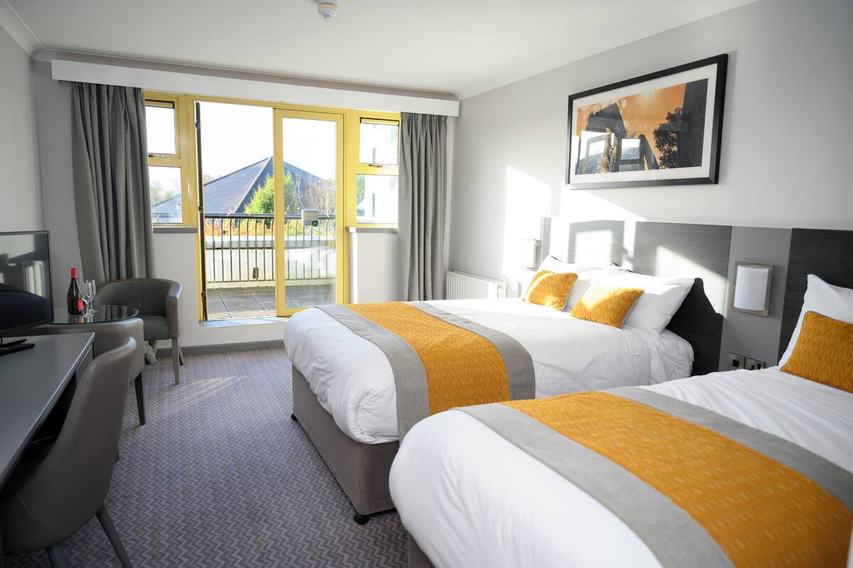 Ein Hotelzimmer mit zwei Betten, einem Schreibtisch und einem Sessel.