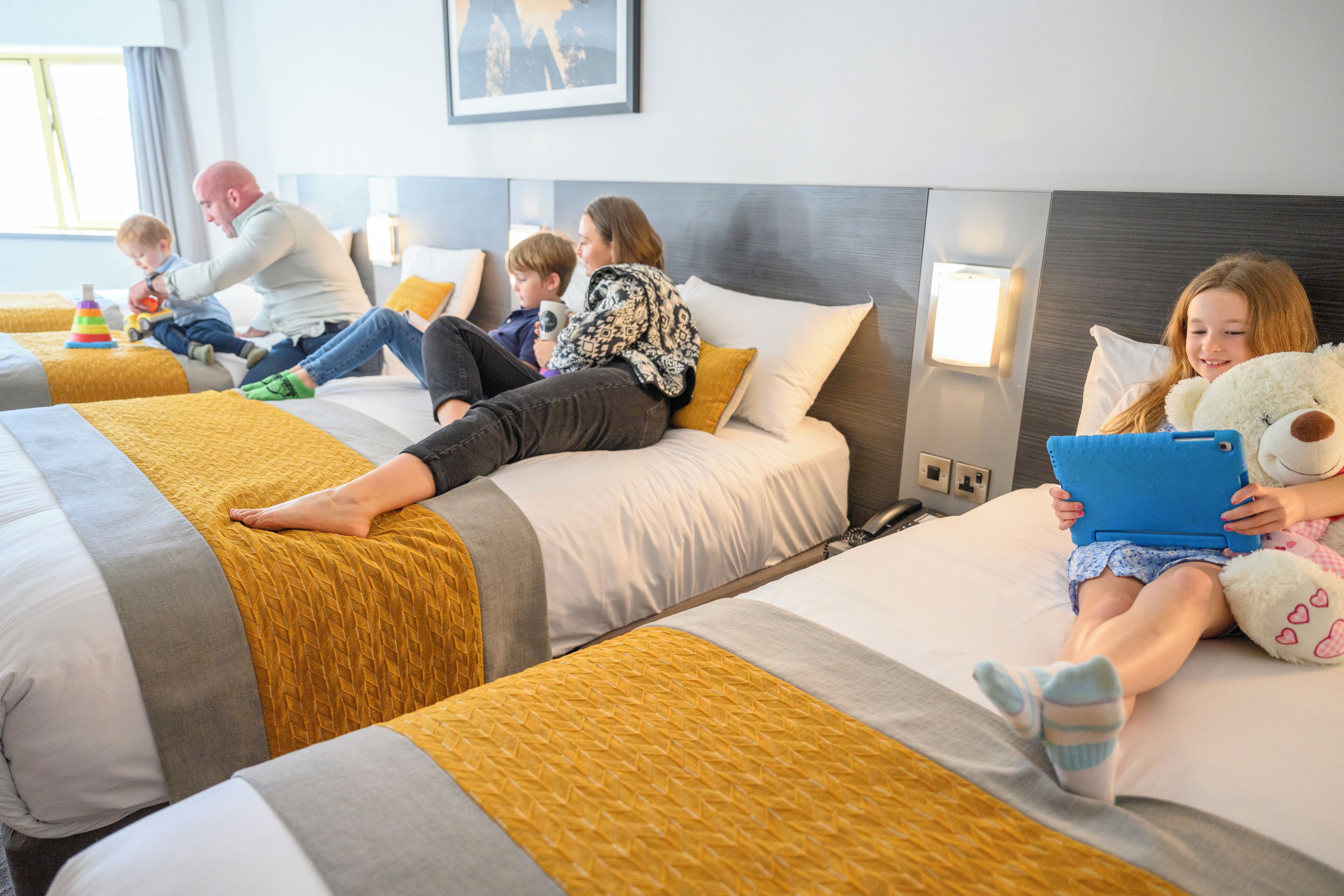 A hotel room with two beds, a headboard, and a wall-mounted light.