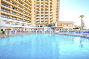 Una piscina techada, una piscina al aire libre, sombrillas