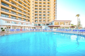 A hotel with a large swimming pool surrounded by blue lounge chairs and a multi-story building with balconies. - Globales Gardenia (Fuengirola)