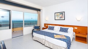 A hotel room with a large bed, a bedside table, a nightstand, a chair, a window with a view of the sea, and a framed picture on the wall. - Globales Gardenia (Fuengirola)