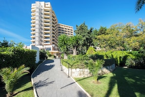 A multi-story hotel with a central courtyard, surrounded by lush greenery and a paved walkway. - Globales Gardenia (Fuengirola)