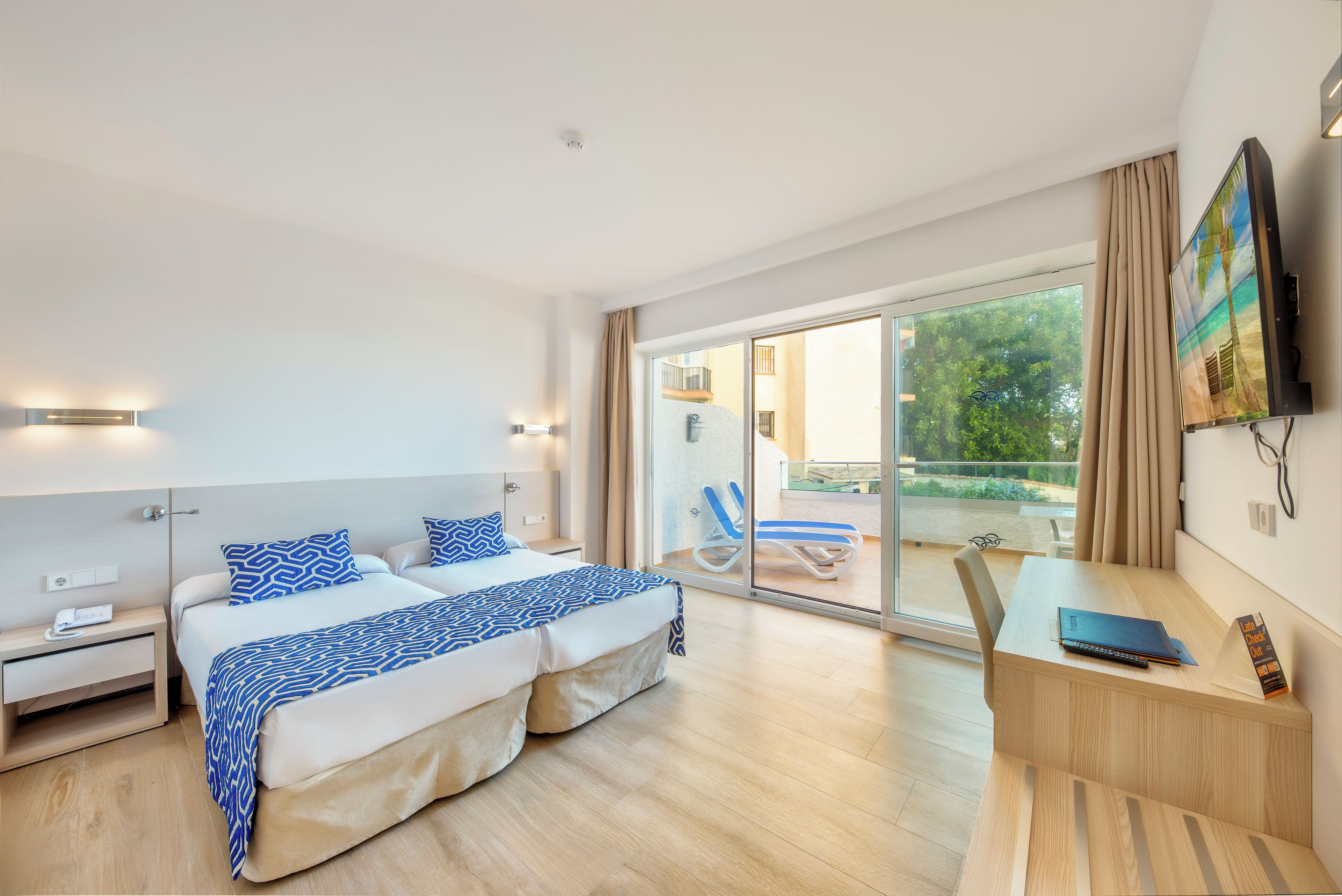 Una habitación de hotel moderna con una cama grande, un escritorio y un balcón con una silla.