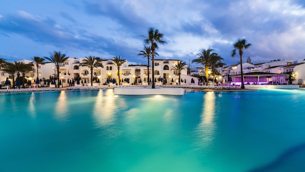 A resort with a large pool, palm trees, and white buildings. - Globales Aparthotel Bouganvilla (Sant Llorenc des Cardassar)