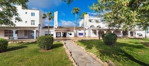 A hotel with a central courtyard, palm trees, and a clear sky. - Globales Aparthotel Bouganvilla (Sant Llorenc des Cardassar)