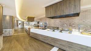 A modern kitchen with a long counter, wooden cabinets, and a brick wall. - Globales Aparthotel Bouganvilla (Sant Llorenc des Cardassar)