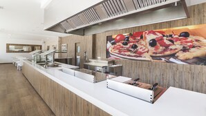 Cocina moderna con una barra alargada, electrodomésticos de acero inoxidable y un póster grande de pizza en la pared.
