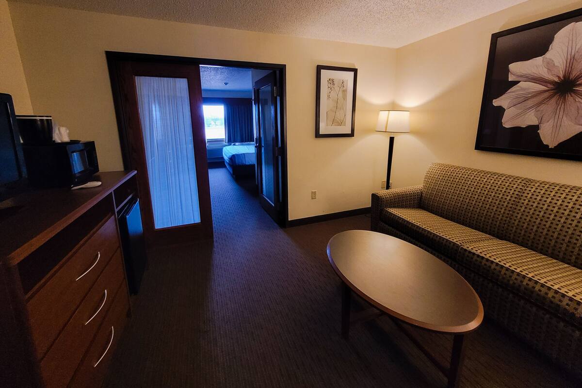 Ein Hotelzimmer mit Bett, Sofa, Tisch, Fernseher und Lampe.