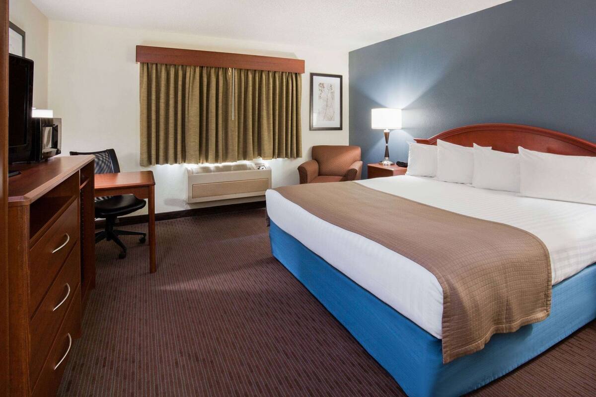 Ein Hotelzimmer mit Bett, Schreibtisch, Stuhl und Wandheizung.