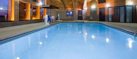 Una piscina interior con vigas de madera y amplias ventanas.