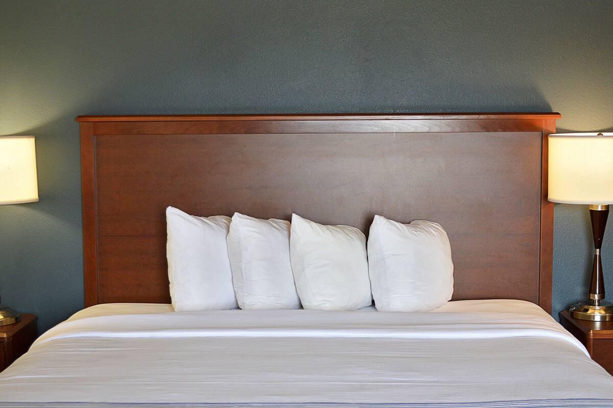 Ein Hotelzimmer mit einem großen Bett, einem Holzkopfteil und zwei Nachttischlampen.