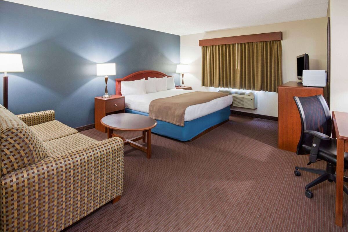 Ein Hotelzimmer mit Bett, Schreibtisch, Stuhl, Sofa und einem kleinen Tisch.