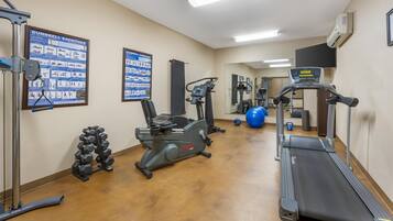 Una palestra con tapis roulant, ellittiche e manubri.