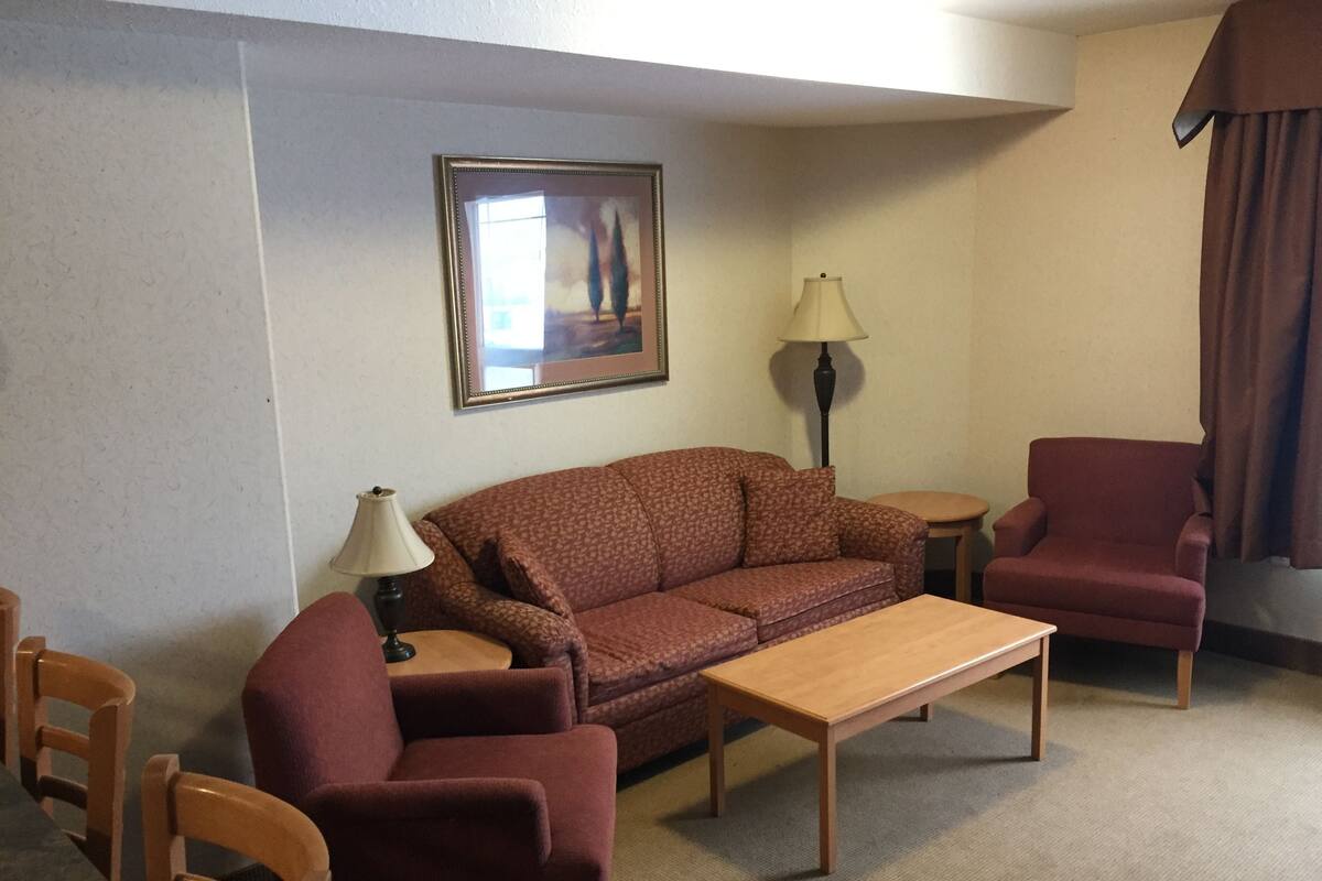 A living room with a sofa, armchair, coffee table, and a lamp.