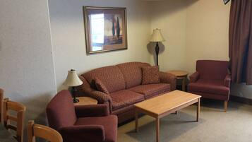 A living room with a sofa, armchair, coffee table, and a lamp.
