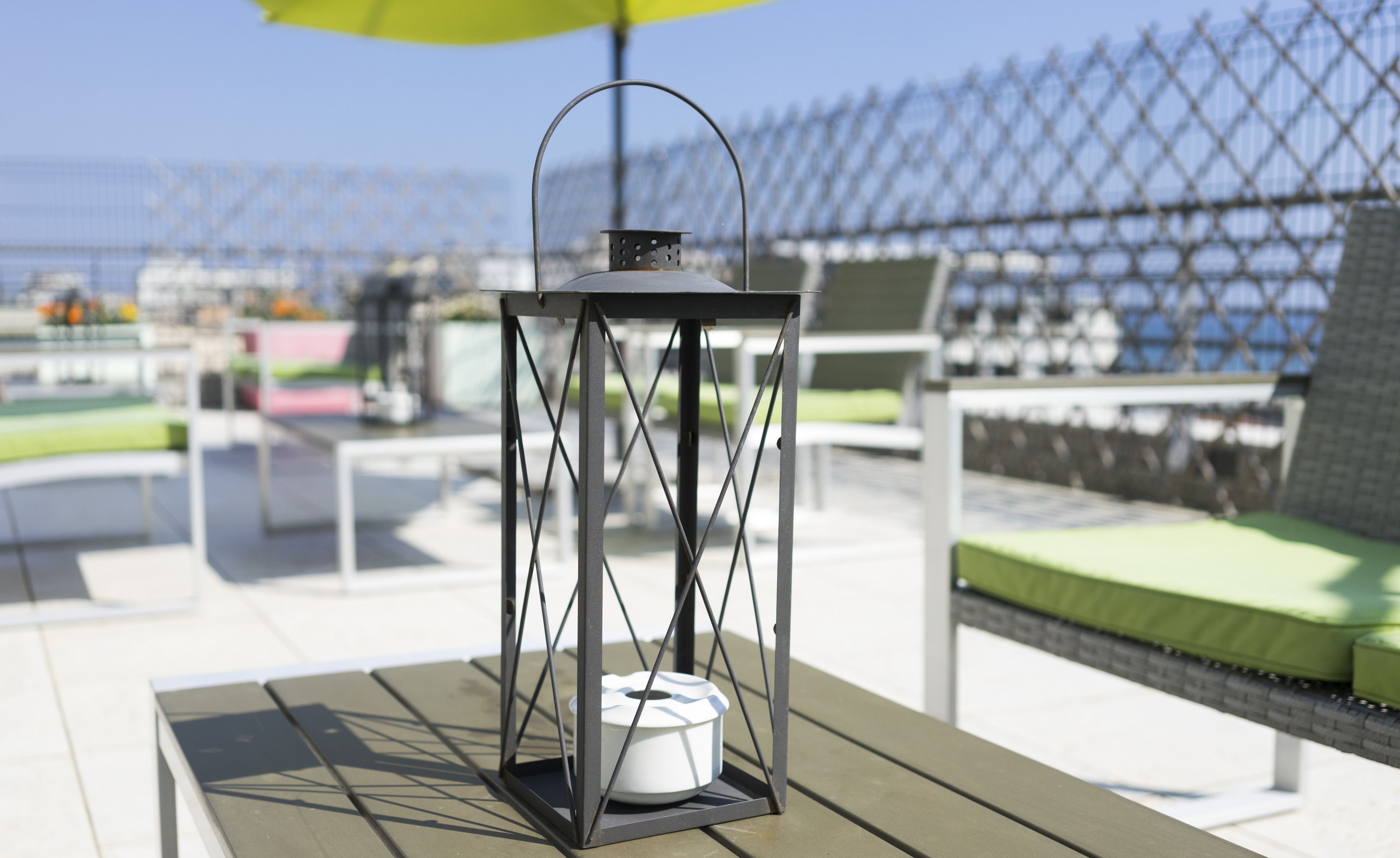Un farol sobre una mesa, con vista a una piscina y sillones de descanso.
