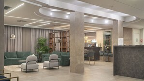A modern lobby with a reception desk, seating area with sofas and armchairs, and a bar area. - Club Meeting Hotel (Rimini)